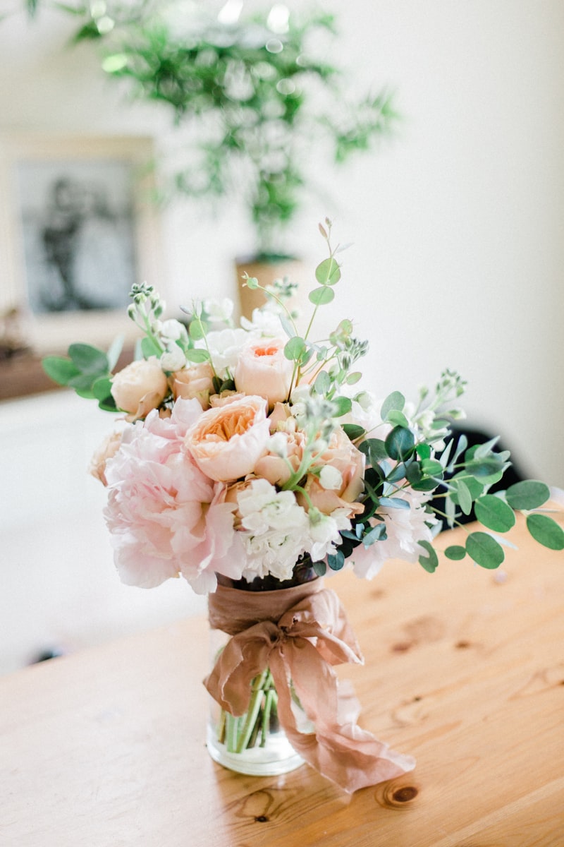 Peach rose bouquet in a glass jar on a wooden table
