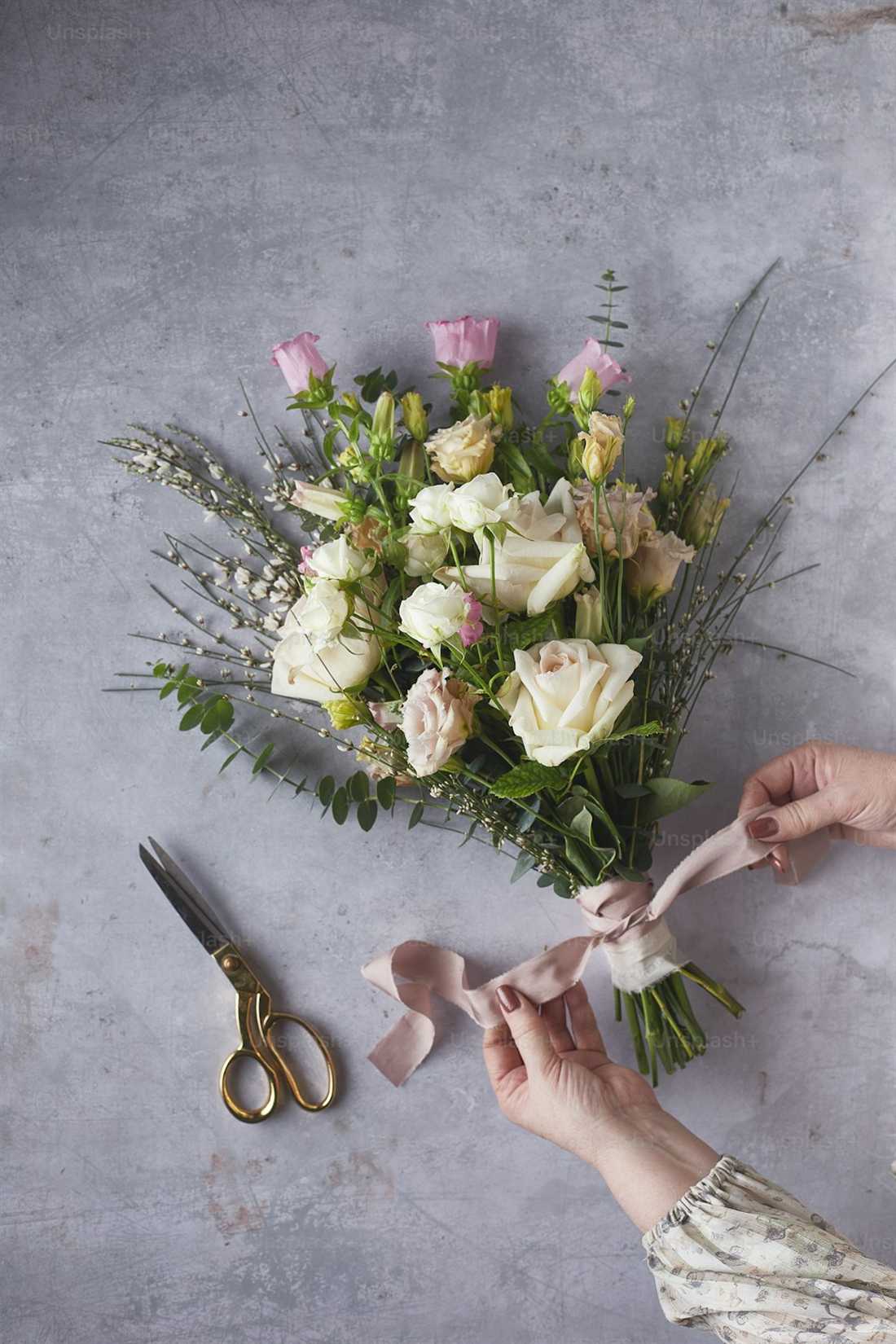 Hands tying a ribbon on a cream and pink bridal bouquet